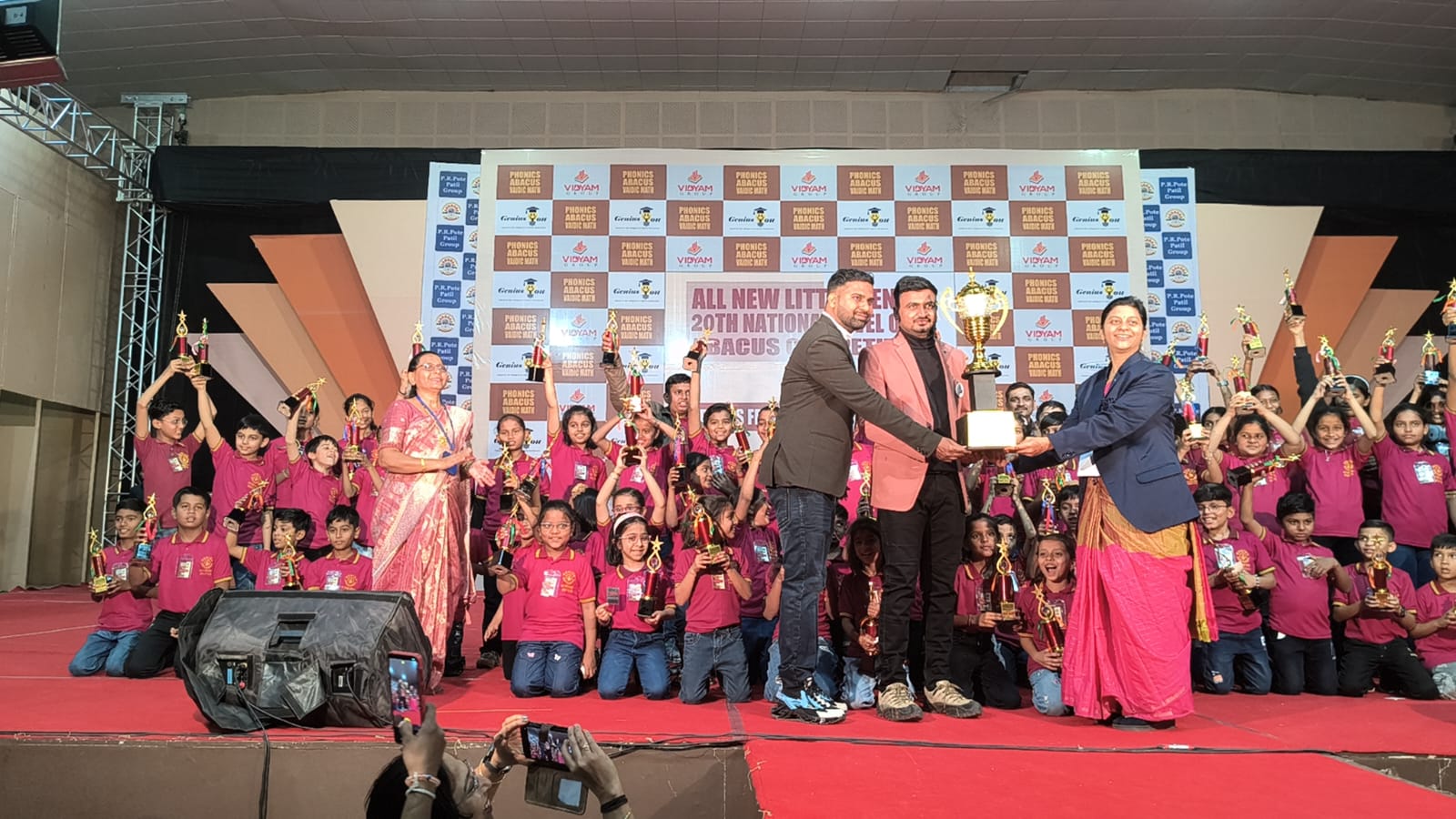 Pooja Bakale on stage receiving franchise award with students